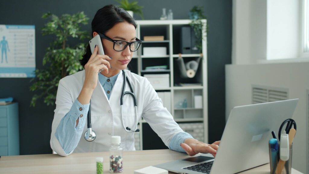 Médecin jonglant entre appel téléphonique et agenda numérique pour la prise de rendez-vous